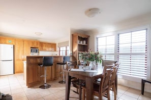 A kitchen with wooden cabinets, a white refrigerator, a microwave, and a dining table with chairs.