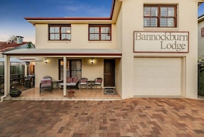 A two-story building with a sign reading "Barnockburn Lodge." There is a covered patio with outdoor furniture and a garage.