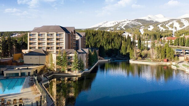 A hotel with a pool, surrounded by mountains and trees.