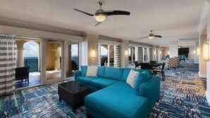 A hotel lobby with a large teal sofa, a coffee table, and two ceiling fans.
