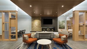 A modern living room with a fireplace, seating area, and built-in bookshelves. - Fairfield Inn & Suites by Marriott Statesville (Statesville)