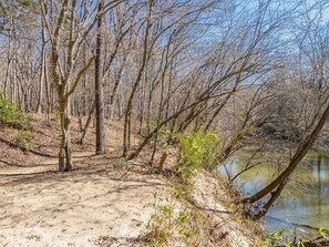 A natural landscape with a dirt path, trees, and a body of water.