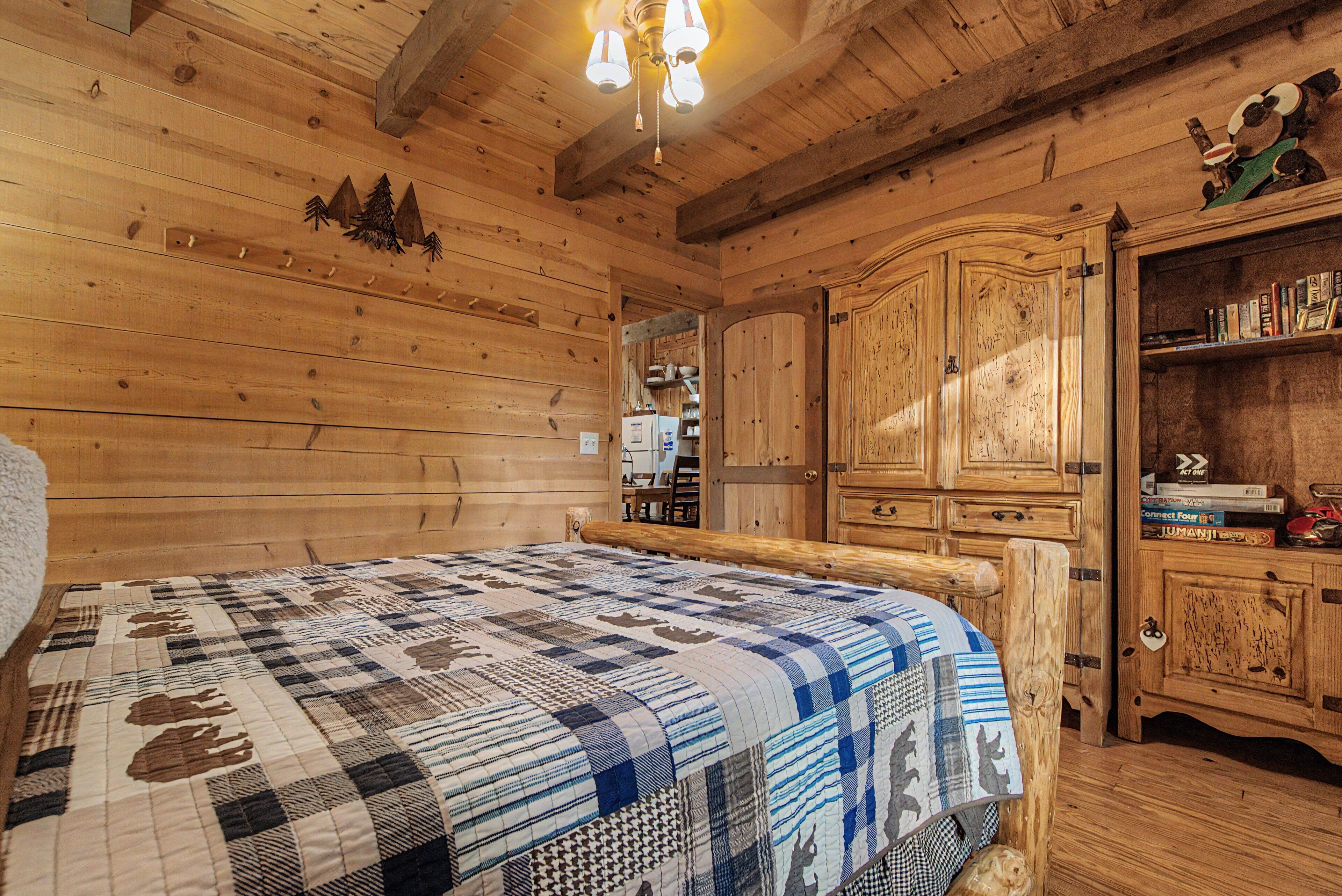Interno di una baita in legno con un letto, un armadio in legno e una mensola piena di libri.