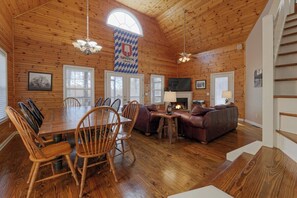 Un intérieur en bois comprenant une table à manger, des chaises, un canapé, une cheminée et un drapeau.