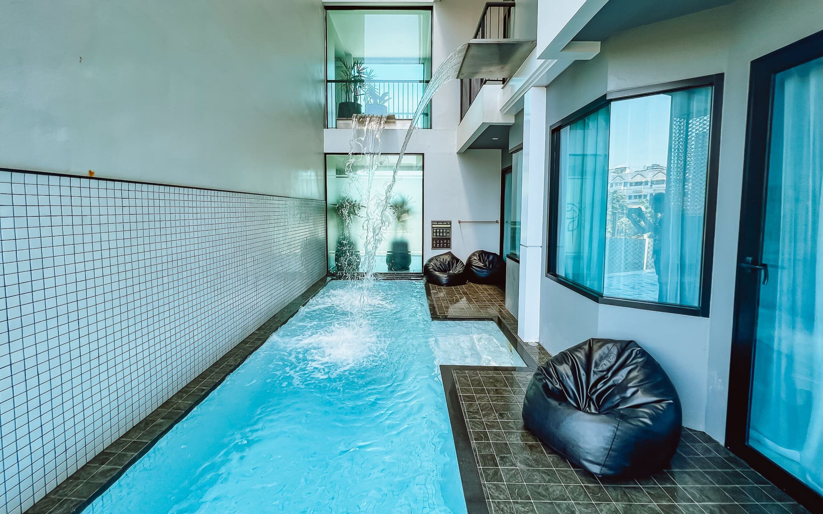 A narrow indoor swimming pool with tiled walls and a black bean bag chair.