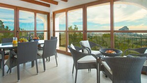 A dining area with wicker furniture, large windows, and a city view. - Villa Aguila with panoramic mountain and sea views, private pool, terraces (Calpe)