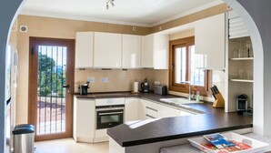 A modern kitchen with white cabinets, a built-in oven, and a large island with a magazine. - Villa Aguila with panoramic mountain and sea views, private pool, terraces (Calpe)