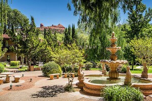A garden with a central fountain, surrounded by neatly arranged benches and trimmed hedges. - Luxury 2BR Red Rock Getaway on Oak Creek at the Arroyo Roble Resort! (Sedona)