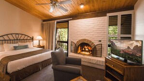 Un dormitorio con cama, una silla, chimenea y televisor.