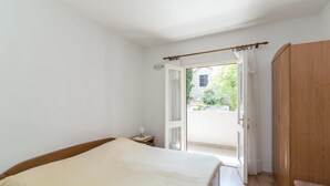 A bedroom with a bed, a wooden wardrobe, and a door leading to a balcony. - Apartment Alana - (Supetar)