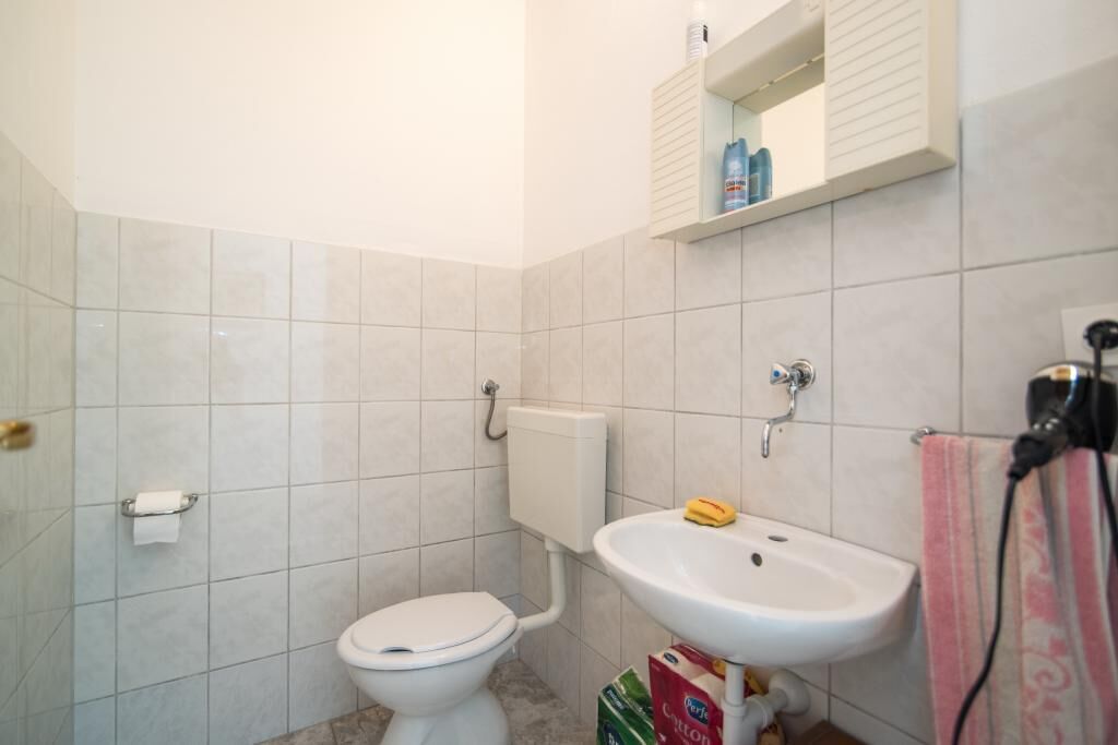 A small bathroom with a toilet, a sink, and a mirror.