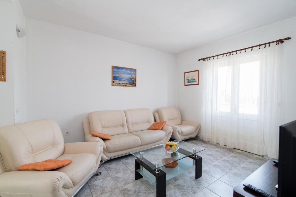 A living room with two beige sofas, a glass coffee table, and a television on a wooden stand.