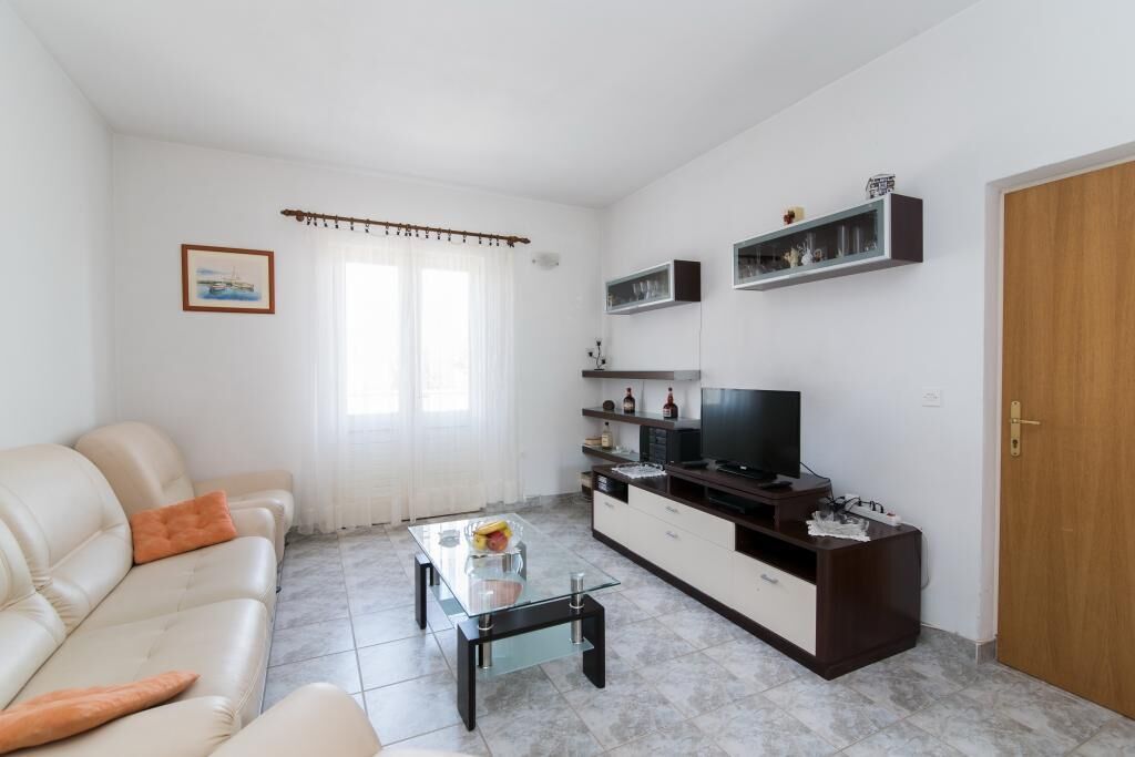 A living room with a sofa, coffee table, TV, and shelves.