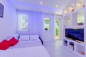 A modern bedroom with a bed, TV, and white shelving unit. - Studio Luce Mala (Split)