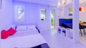 A modern bedroom with a bed, TV, and a dining area with a table and chairs. - Studio Luce Mala (Split)