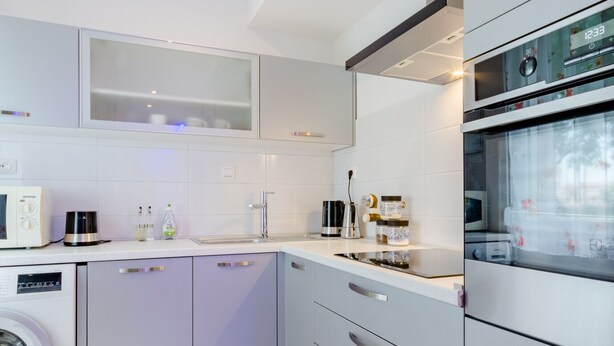 A modern kitchen with a washing machine, a coffee maker, and a microwave. - Studio Luce Mala (Split)