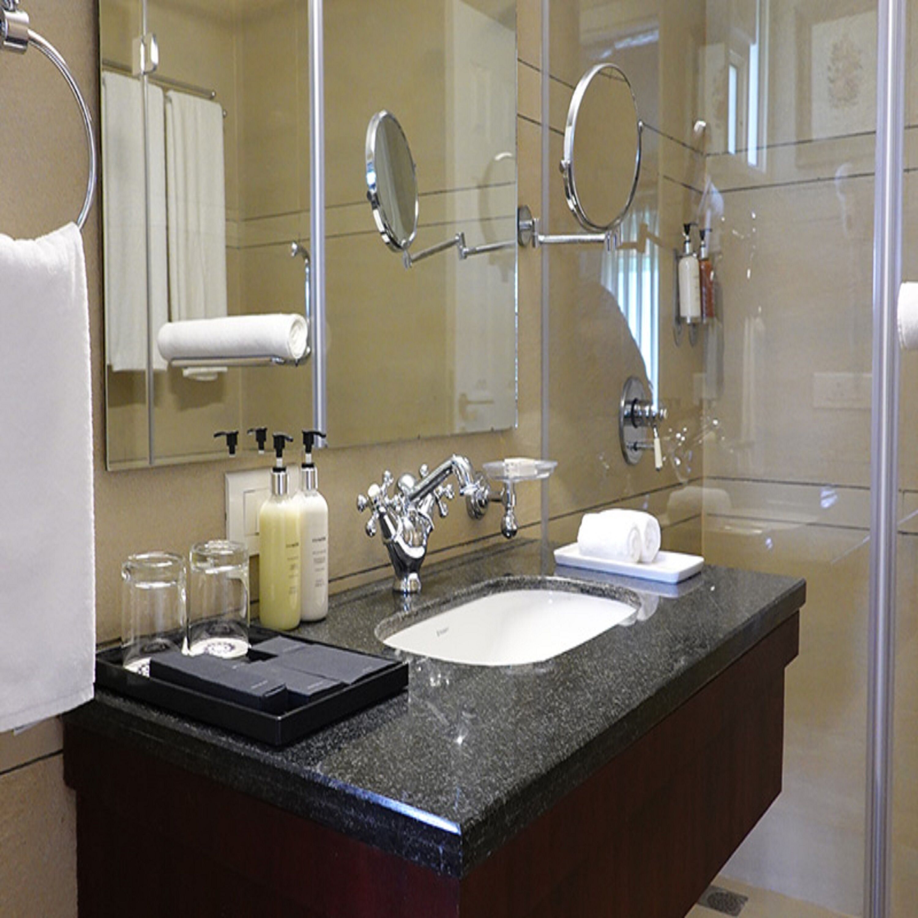 A modern bathroom with a granite countertop, a white sink, and a large mirror.