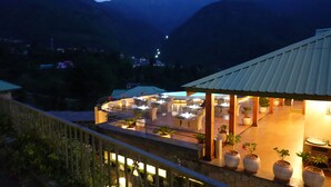 A restaurant with outdoor seating overlooking a mountainous landscape. - Araiya Palampur (Palampur)
