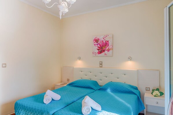 Un dormitorio con una cama grande, dos mesitas de noche, una lámpara de pared y una obra de arte floral.