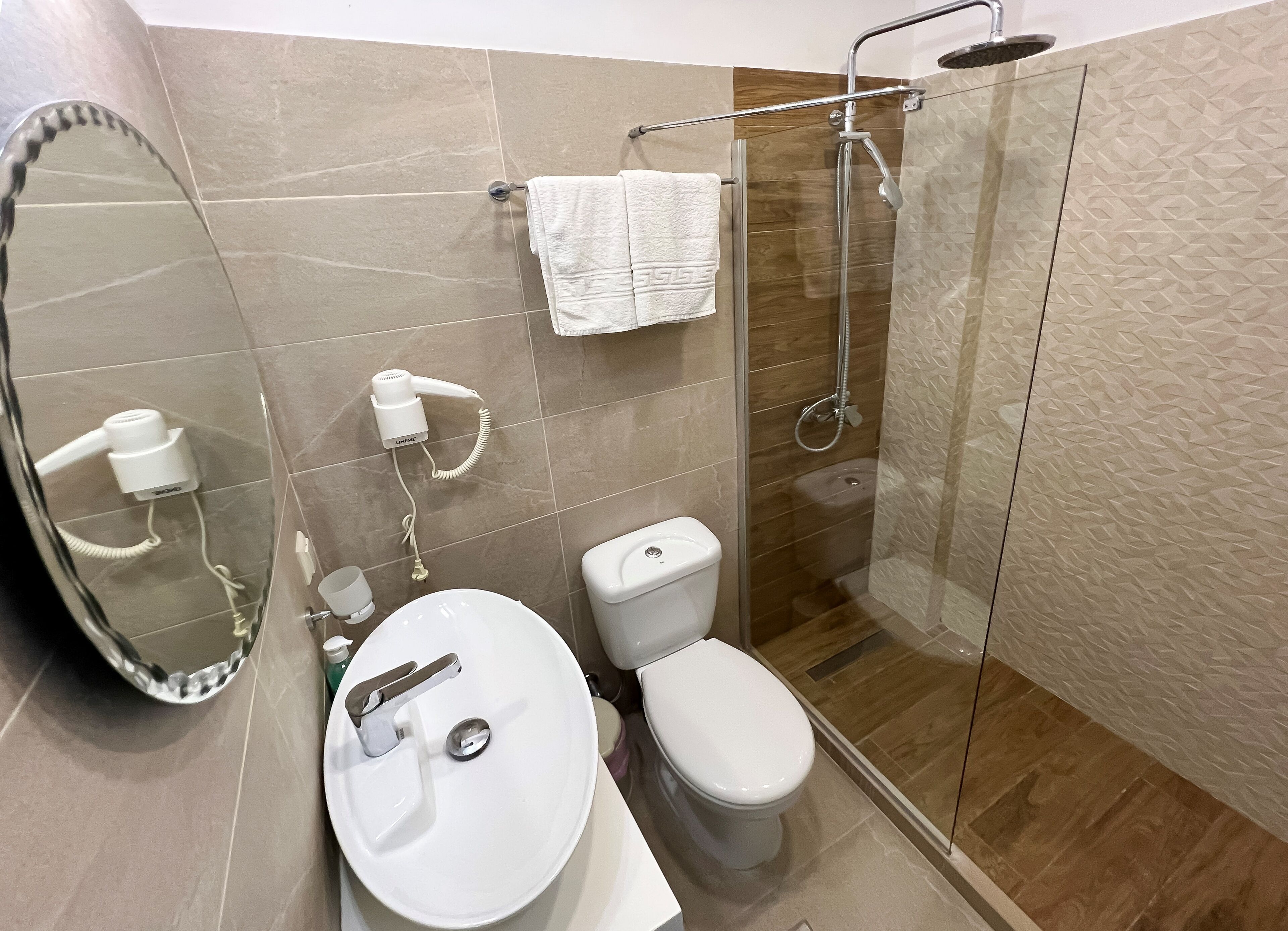 Une salle de bain moderne avec une douche à parois de verre, un lavabo blanc et des toilettes.