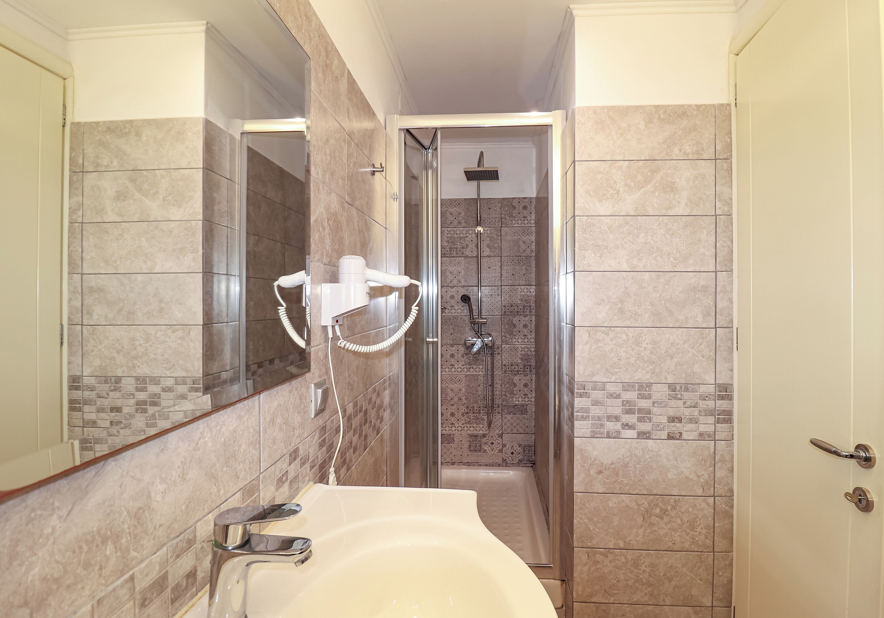 A bathroom with a shower, a sink, and a mirror.