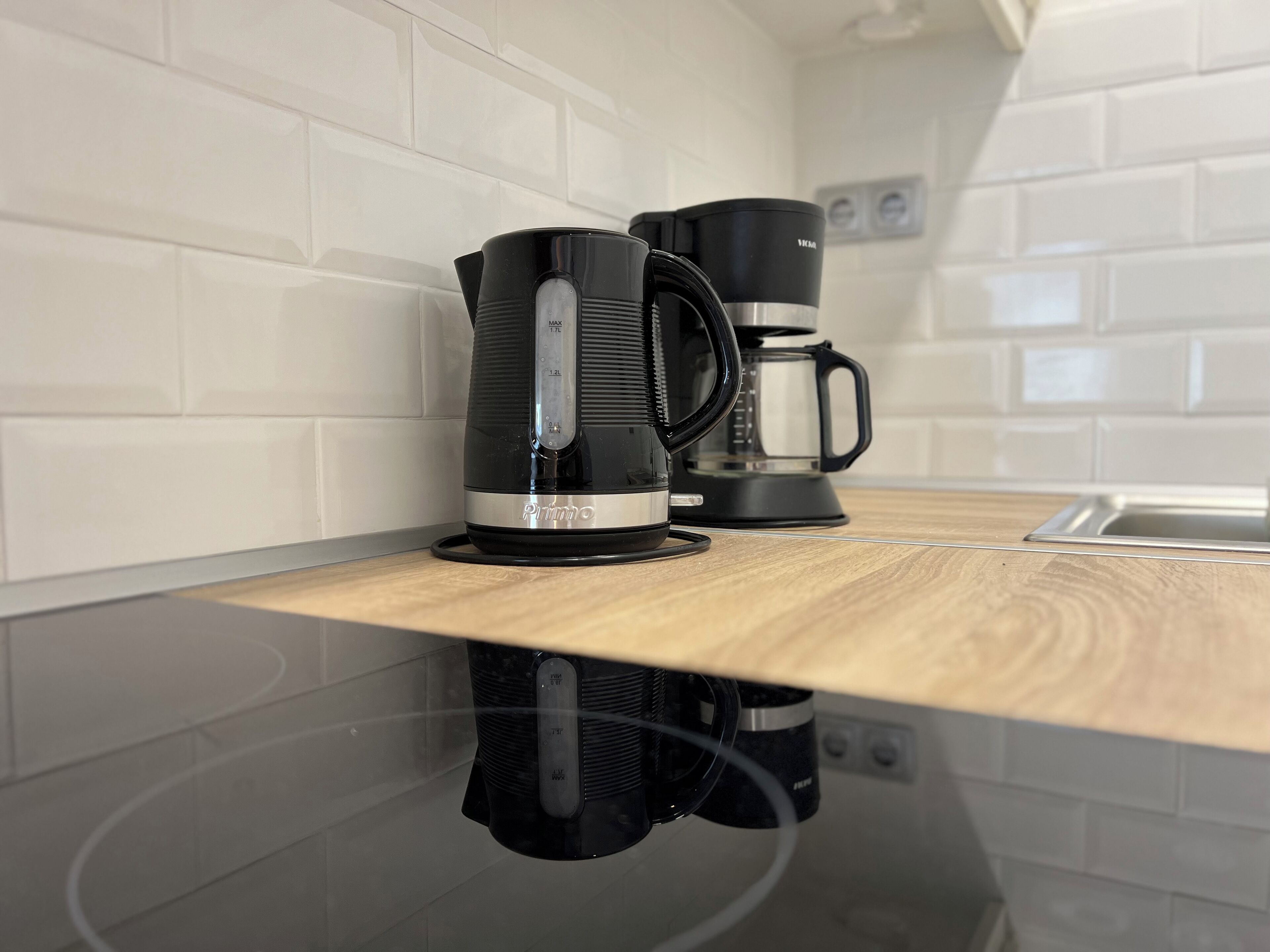 Une cuisine avec une machine à café noire et une bouilloire électrique noire posées sur un plan de travail en bois.