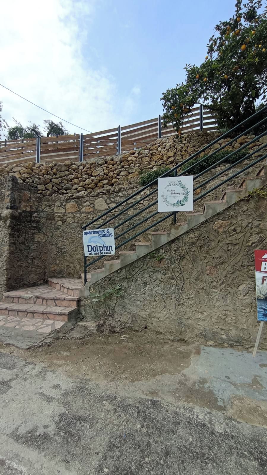 A staircase leading to a stone wall with a sign for Dolphin Apartments & Studios.