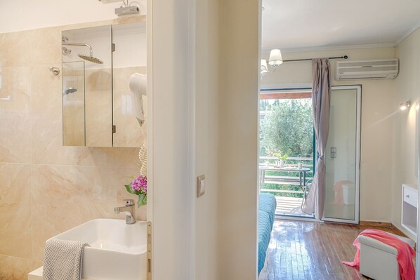 A modern bathroom with a bathtub, a glass shower enclosure, and a visible air conditioning unit.
