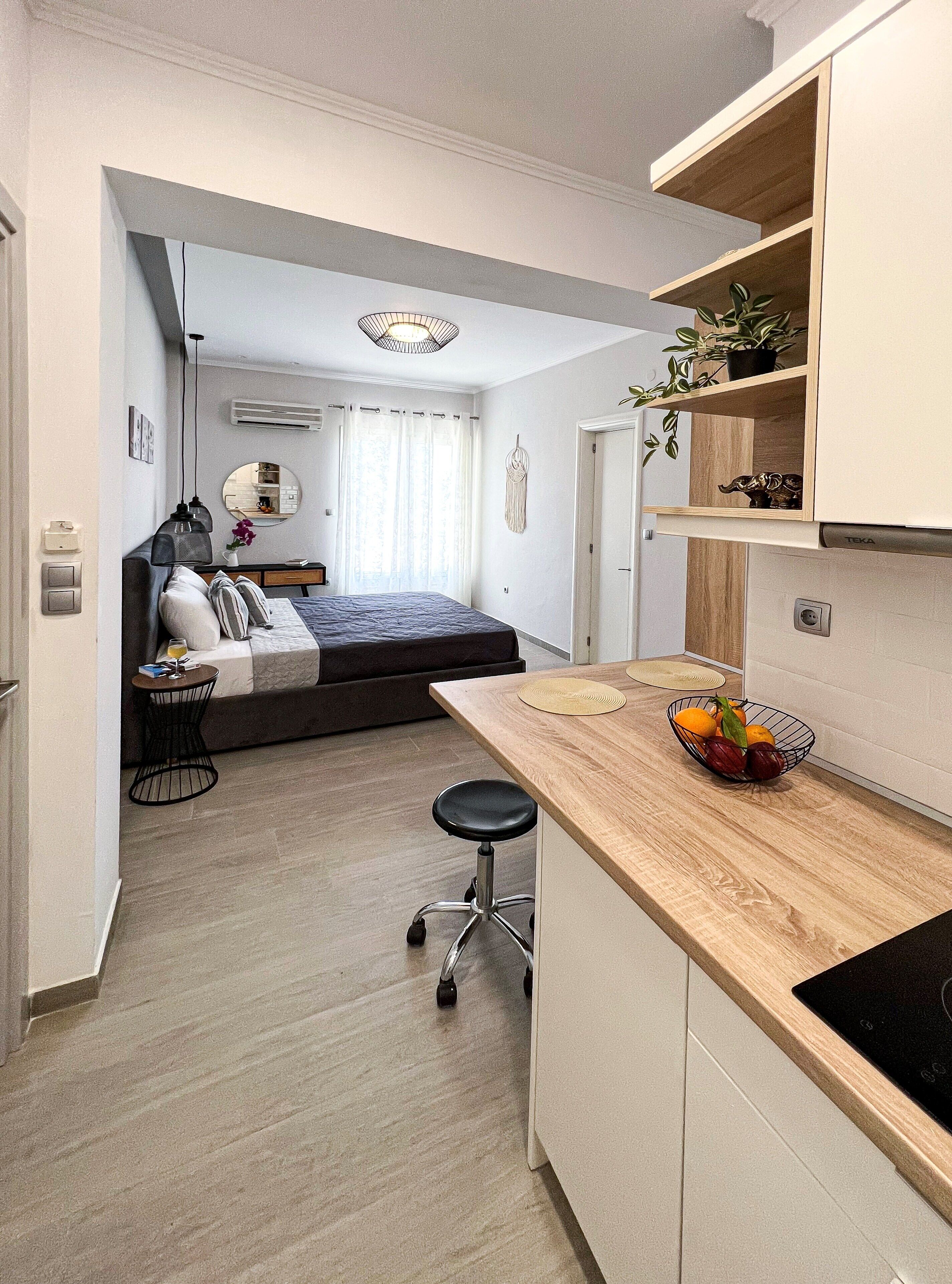 Una habitación pequeña con cama, escritorio y kitchenette.