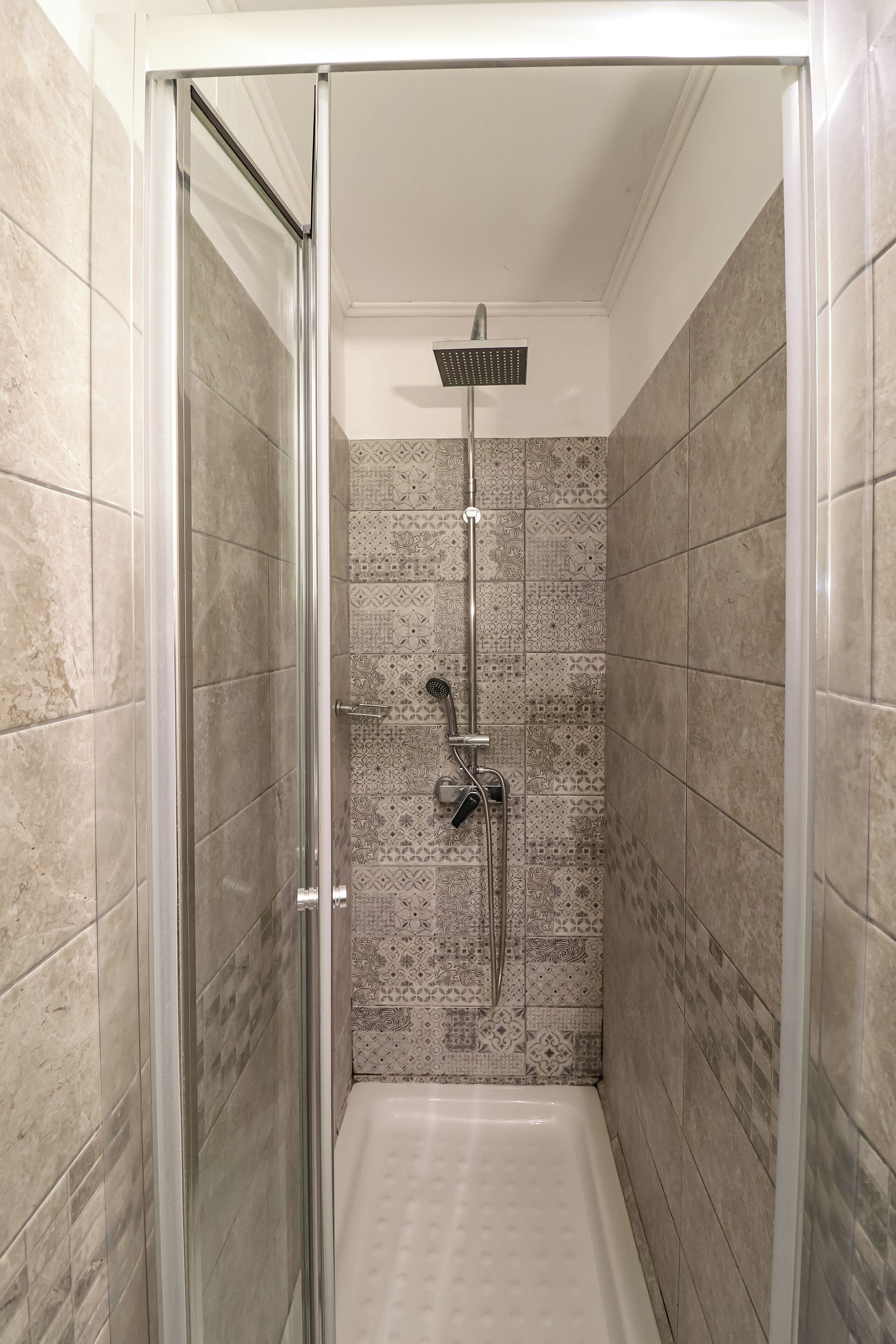 A walk-in shower with a glass door, tiled walls, and a handheld showerhead.