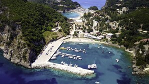 Vue aérienne d’une ville côtière avec un port de plaisance, des falaises rocheuses et une plage.