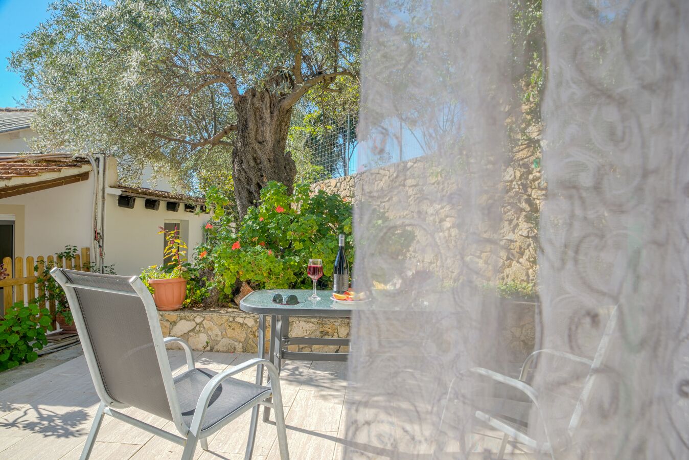 A patio with a table and chairs, a bottle of wine, and potted plants.