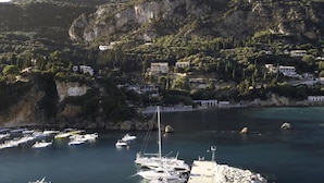 Une zone côtière où des bateaux sont amarrés dans une marina, entourée de maisons et de falaises.