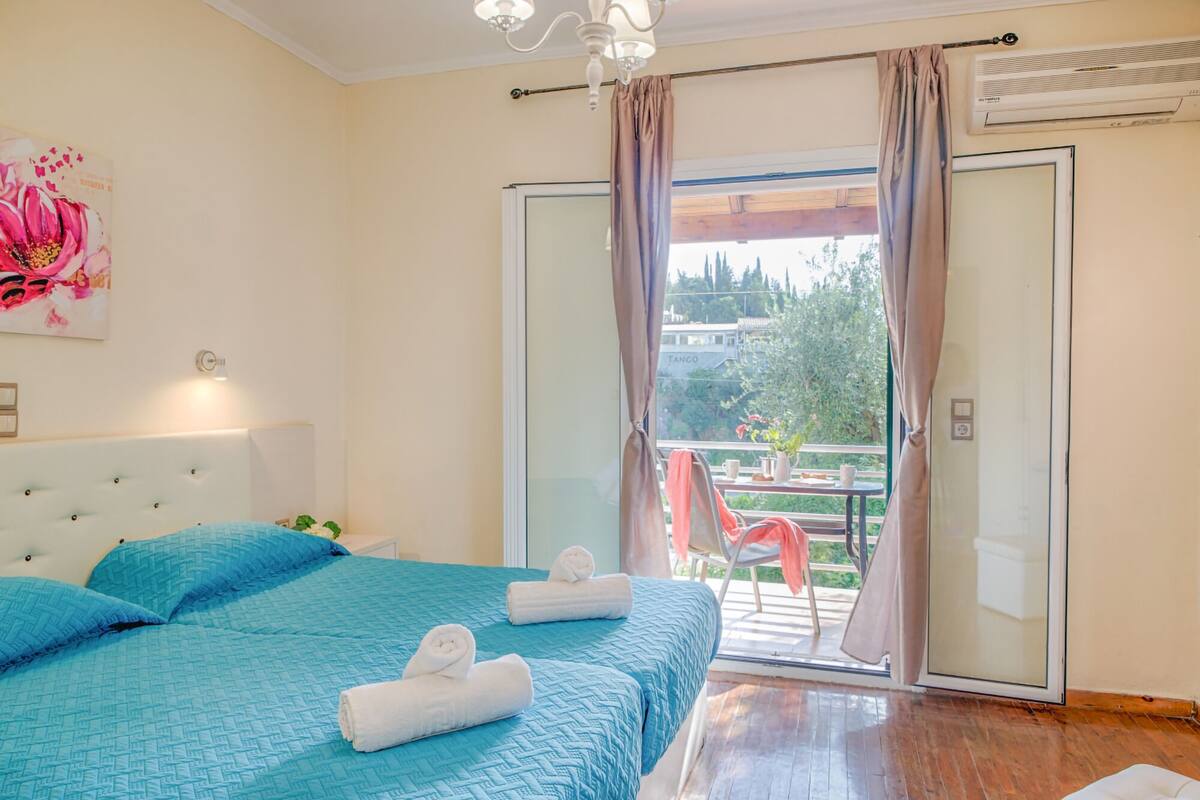 Een slaapkamer met een groot bed, een hoofdeinde, een schilderij en een balkon met uitzicht.