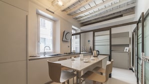 A modern kitchen with a dining area, featuring a large window, built-in appliances, and a wooden ceiling.