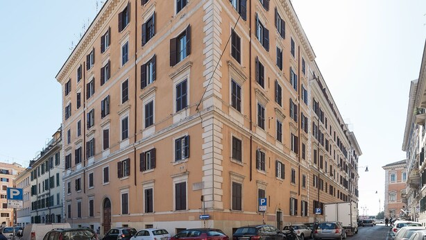 A multi-story building with a classic architectural style, featuring numerous windows and a corner entrance. - Scala Santa & Laterano Open Space (Rome)