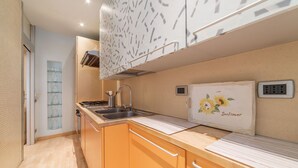 A compact kitchen with a sink, stove, and a decorative wall piece. - Scala Santa & Laterano Open Space (Rome)