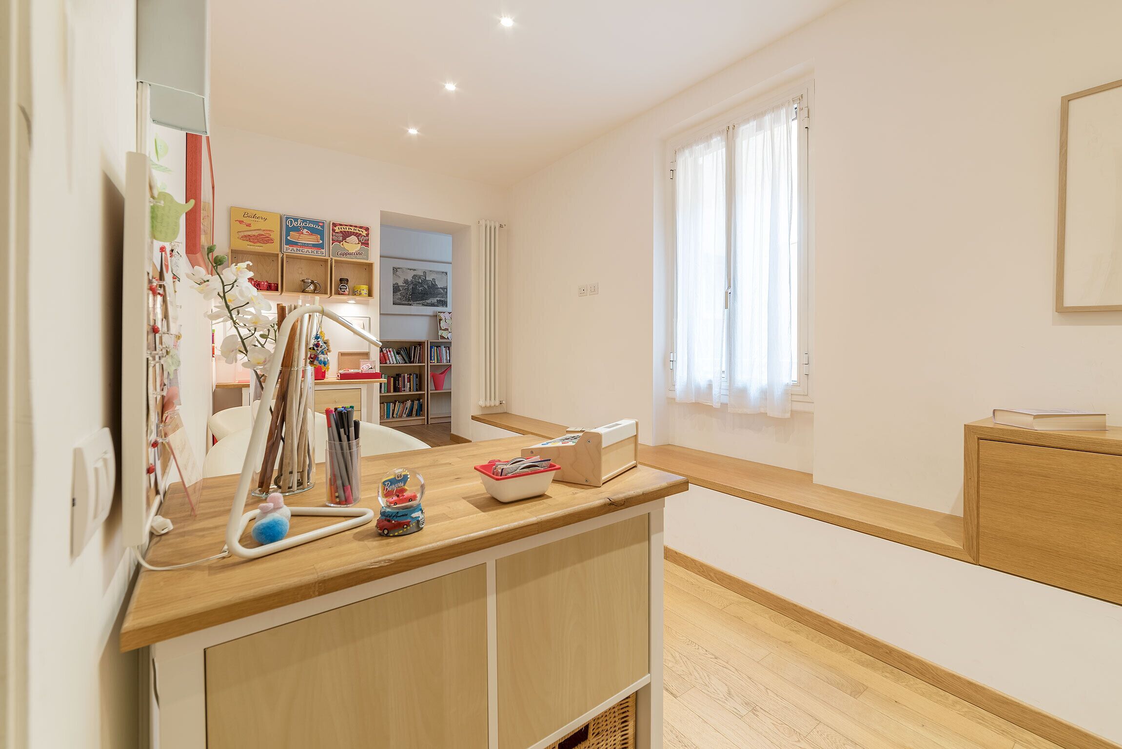 Une pièce bien éclairée, avec un bureau en bois, une bibliothèque et une fenêtre avec des rideaux.