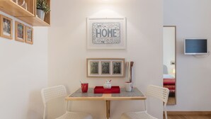 A room with a wooden table, two white chairs, a red tray, and framed pictures on the wall. - Santa Maria Maggiore Exclusive Apartment (Rome)