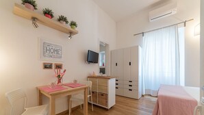 A bedroom with a wooden bed, a bedside table, a chair, a wardrobe, a television, and a window with curtains. - Santa Maria Maggiore Exclusive Apartment (Rome)