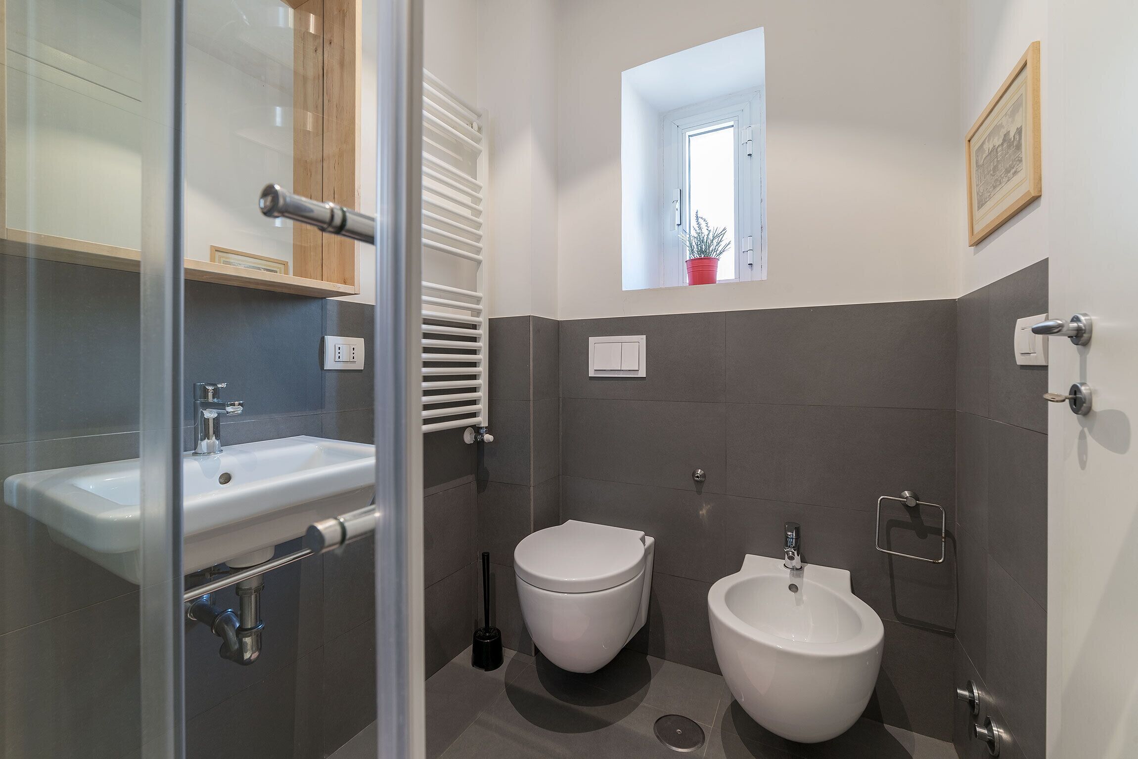Un baño moderno con cabina de ducha de vidrio, un lavabo blanco, un inodoro y un bidé.