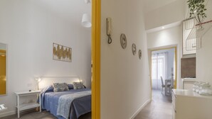 A bedroom with a bed, bedside table, and a wall-mounted telephone. - San Lorenzo Modern Flat (Rome)
