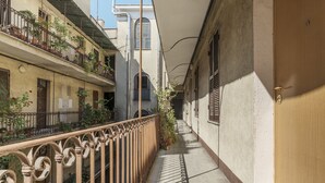 A narrow alleyway with a balcony on the left, a door on the right, and a building with a window in the background. - San Lorenzo Modern Flat (Rome)