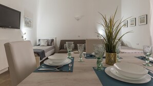 A dining area with a table set for four, a sofa, a bed, and a TV mounted on the wall. - San Lorenzo Modern Flat (Rome)