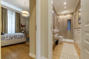 A hotel room with a bed, bedside table, and a large window with curtains.