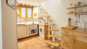 A compact kitchen with a built-in washing machine, a microwave, and a wooden countertop.