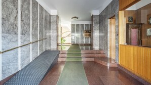 A marble-floored hallway with a green carpet leading to a reception area.