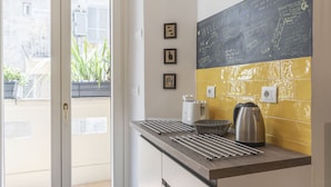 Cozinha com parede de quadro negro, varal de roupas, chaleira e cesta.