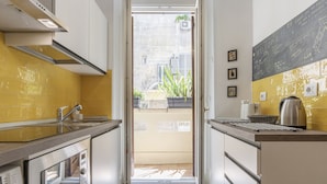 Cozinha moderna com eletrodomésticos de aço inoxidável, painel de azulejos amarelos e vista para o exterior.