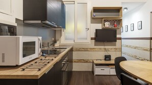 A compact kitchen with a microwave, stove, and wooden countertop. - Roma Termini Big Apartment (Rome)